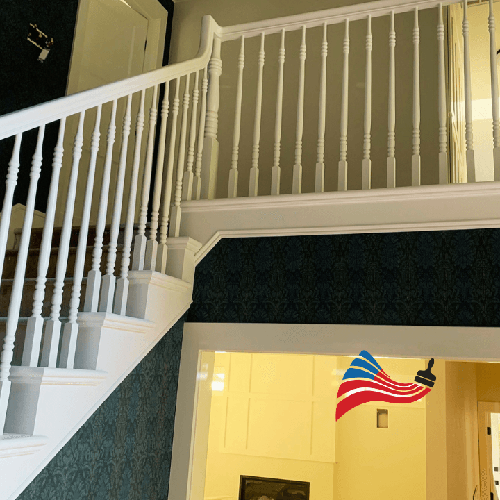 Freshly painted white staircase and banister set against elegant dark blue damask patterned wallpaper.