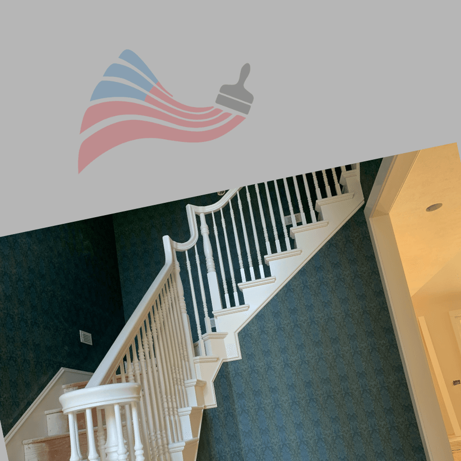 White wooden staircase with spindles against green patterned wallpaper under a paintbrush flag logo.