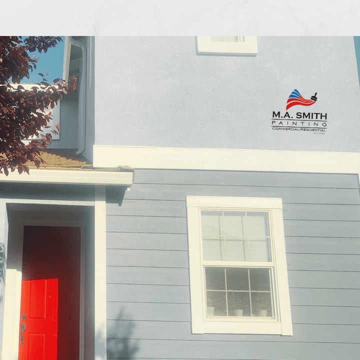 Blue house exterior with white trim, red door, and M.A. Smith Painting company logo.