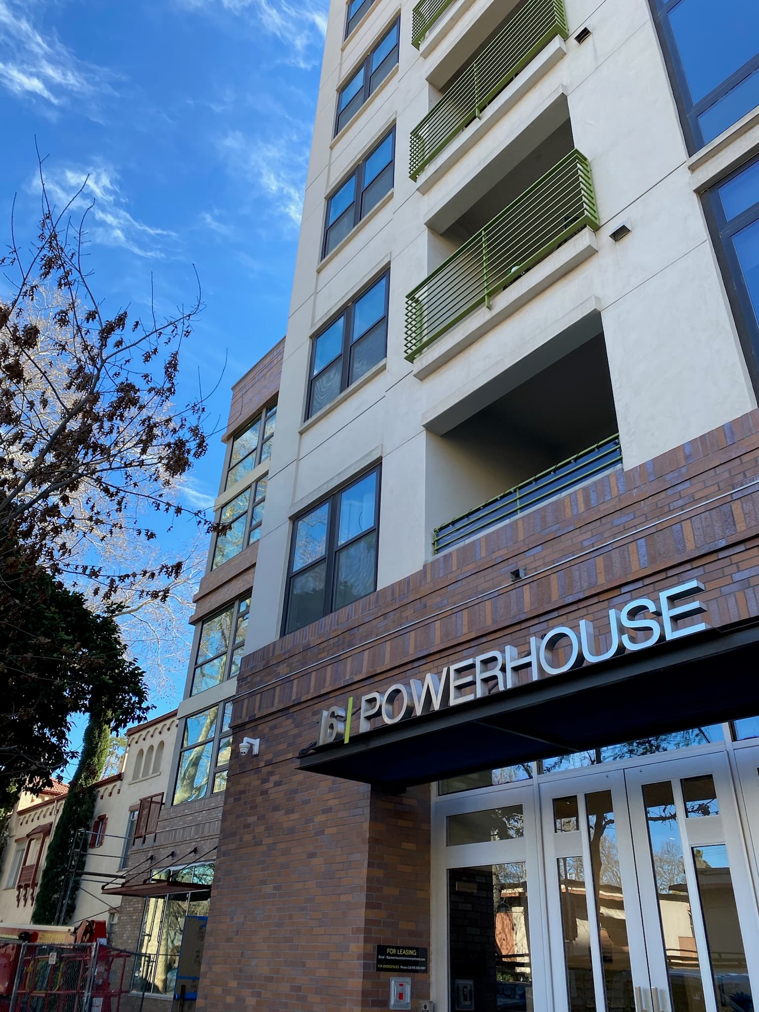 Modern white apartment building named 16 Powerhouse with brick accents and green balcony railings.