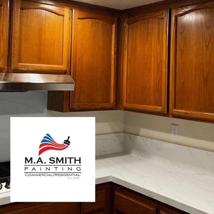Wooden kitchen cabinets and white marble countertops with an M.A. Smith Painting logo overlay.